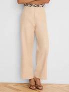 Light beige wide-leg pants, high-waisted, with visible linen texture, falling to the ankles.