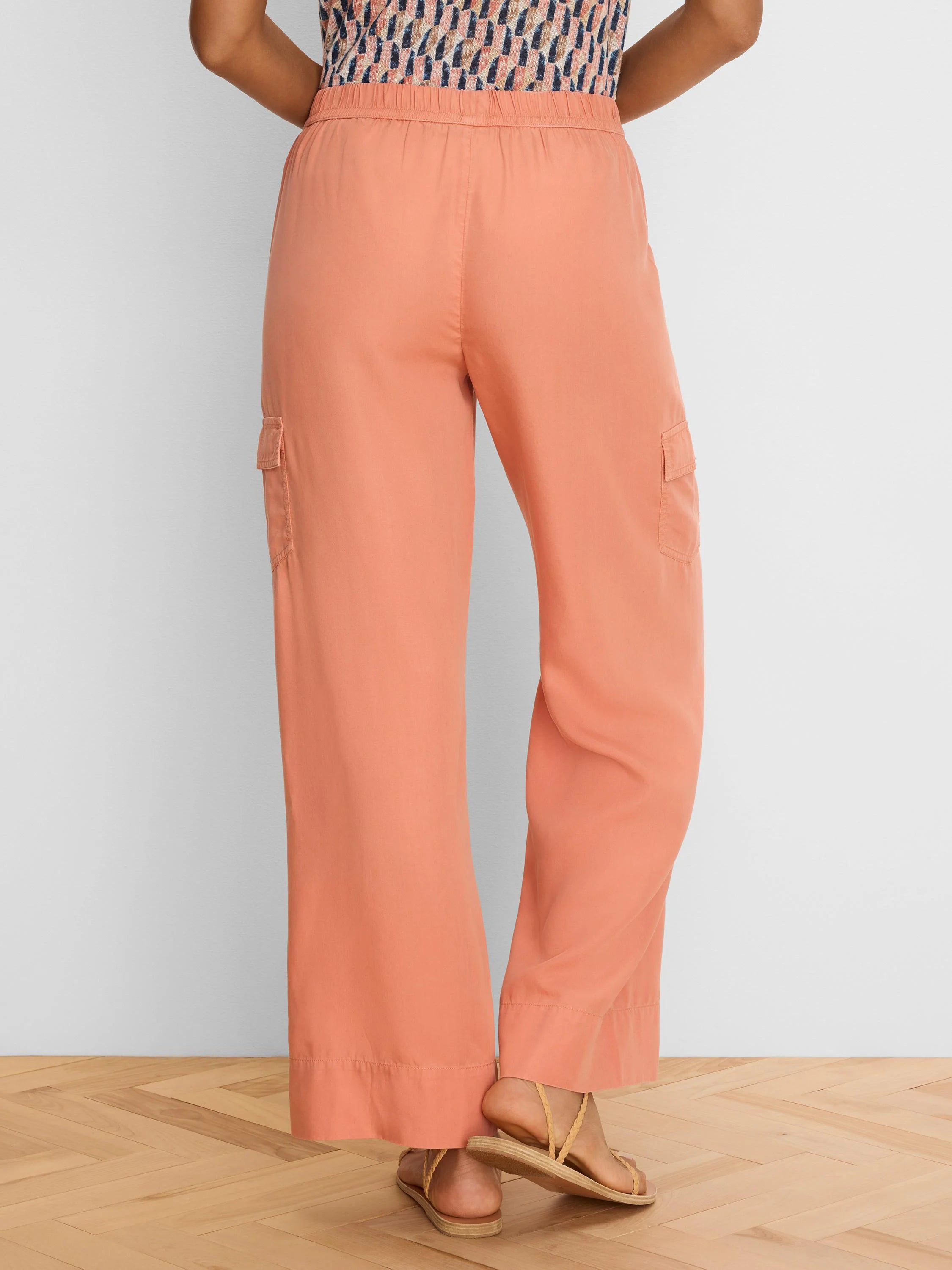 Peach wide leg drapey cargo ankle pants with side pockets and elastic waist, viewed from the back.