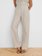 Tan wide-leg linen pants with thin white vertical stripes.