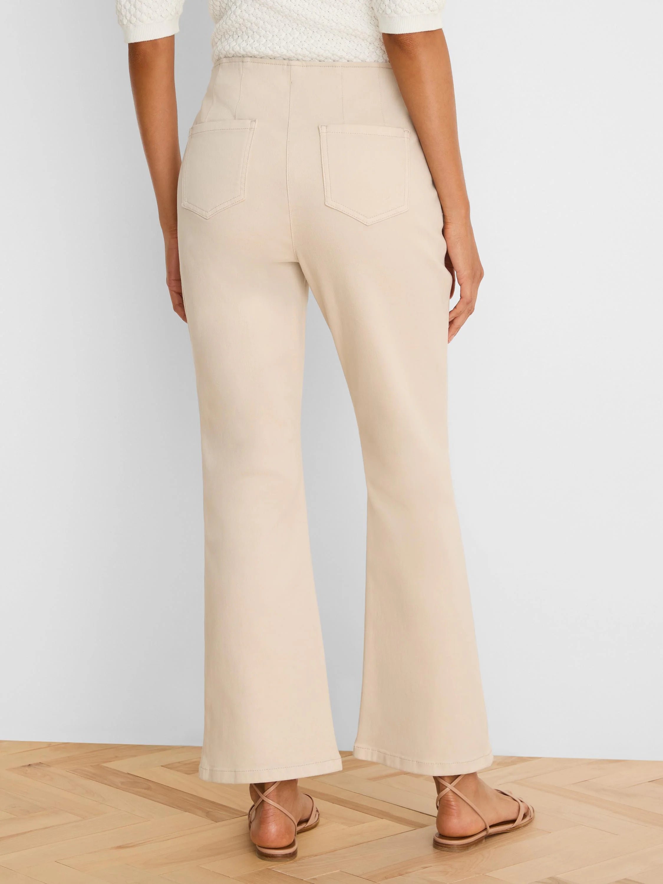 Light beige high-waisted bootcut jeans, viewed from behind, with back patch pockets and visible stitching.
