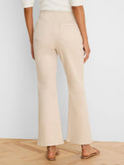 Light beige high-waisted bootcut jeans, viewed from behind, with back patch pockets and visible stitching.