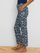 Dark blue ankle pants with white shibori lily pattern. Straight cut, ankle length. Model's hand in pocket.