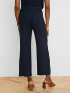 Navy wide-leg linen crop pants with a braided self-belt and two large rear patch pockets, viewed from behind.