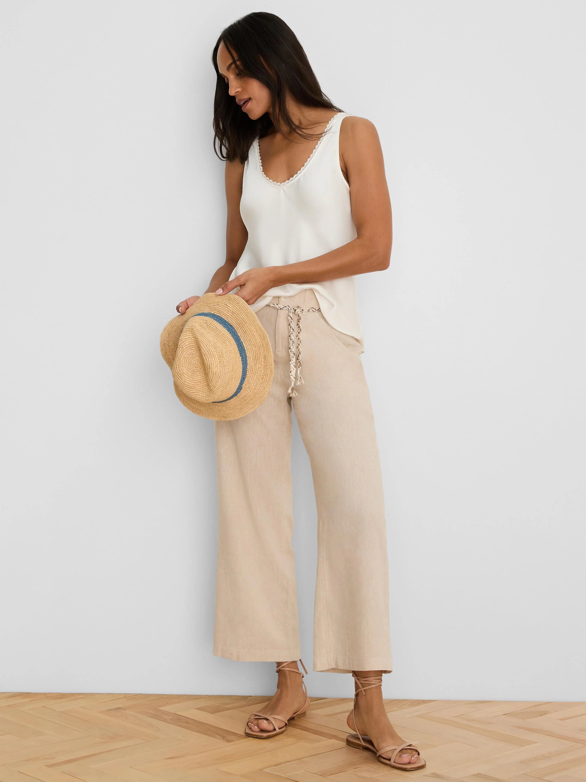 Light beige wide-leg linen crop pants feature a textured braided belt.