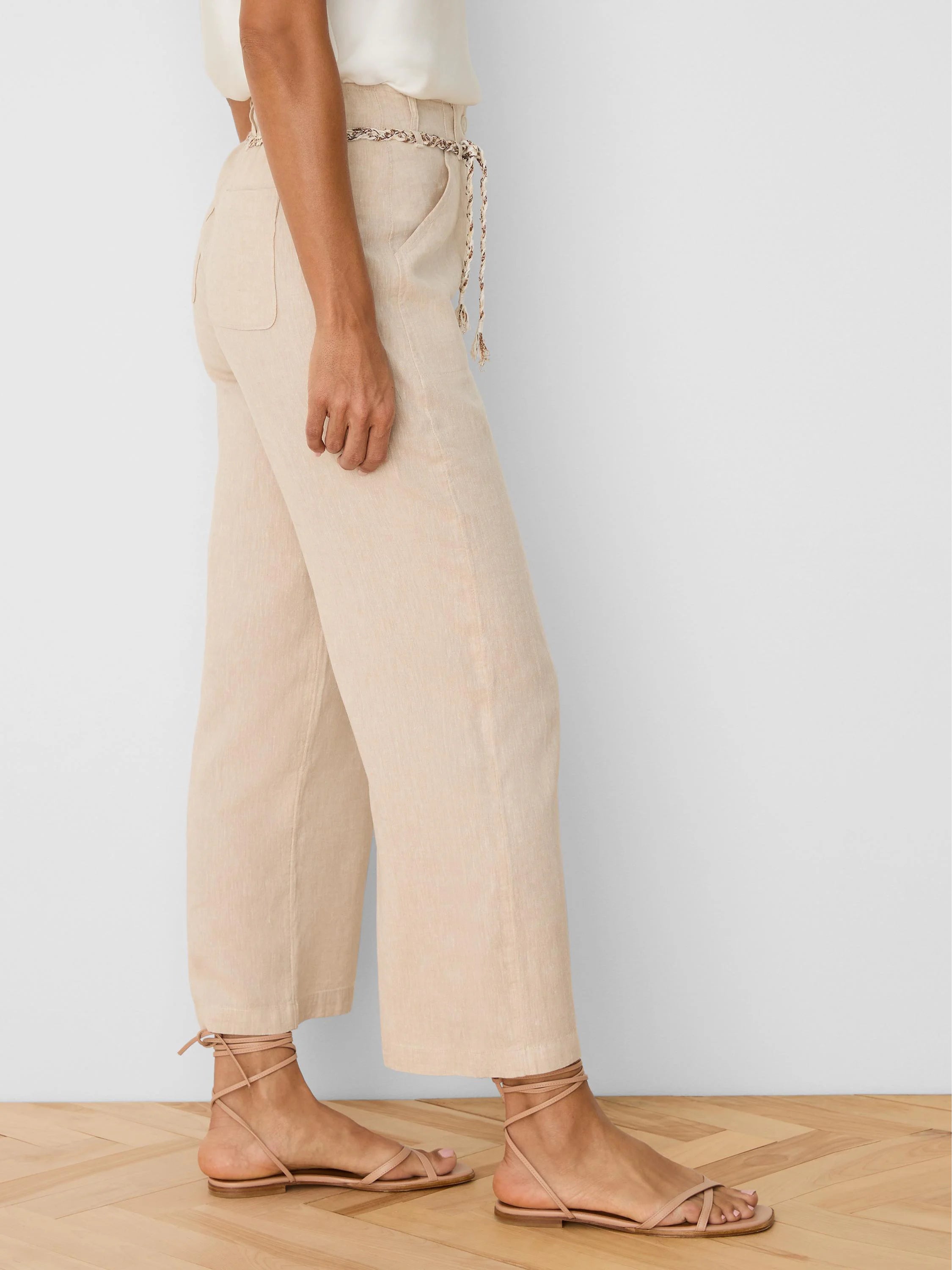 Beige wide-leg linen crop pants with a braided tie belt at the waist and side pockets.