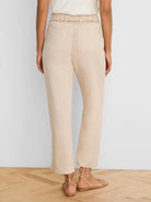 Beige wide-leg linen crop pants, seen from behind. Features a braided belt and two back patch pockets.