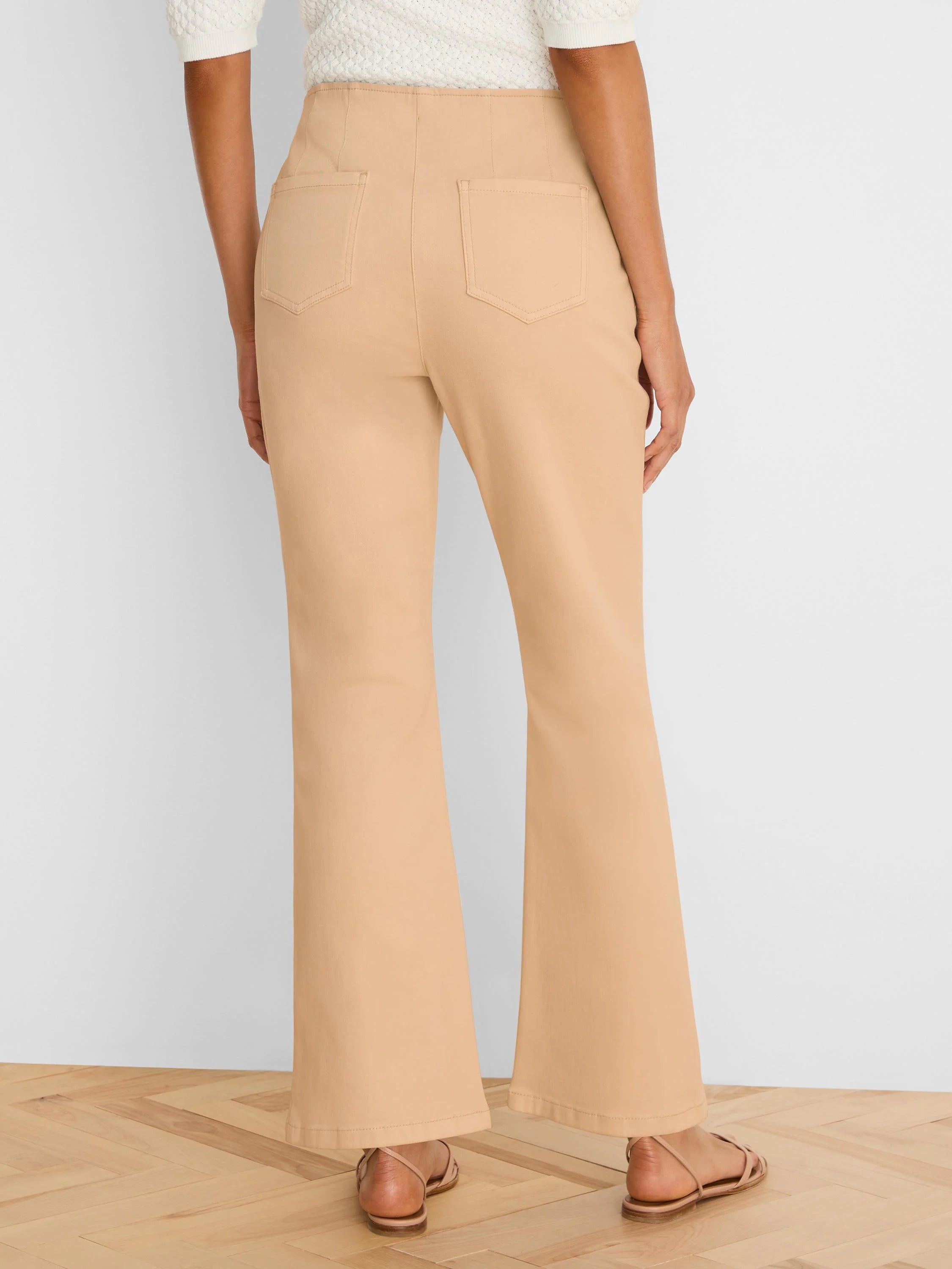 Light tan high-waisted bootcut jeans, seen from the back. Features two patch pockets and a flared leg opening.