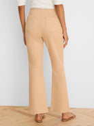 Light tan high-waisted bootcut jeans, seen from the back. Features two patch pockets and a flared leg opening.