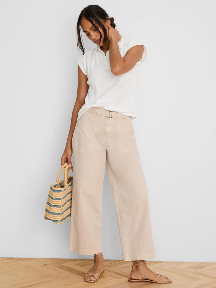 Pale beige wide-leg ankle pants with a self-belt, rectangular buckle, and front patch pockets.