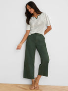 Dark green wide-leg ankle pants with a prominent belt, buckle, and visible vertical seams.