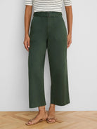Dark green wide-leg ankle pants feature a belted high waist with a square buckle and prominent front patch pockets.