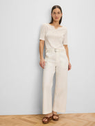 Cream wide-leg belted ankle pants with a rectangular buckle and side pockets.