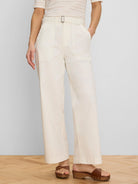 Cream wide-leg ankle pants with a fabric belt, black rectangular buckle, and front patch pockets.
