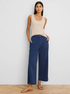 Dark blue wide-leg ankle pants with a belted waist, square silver buckle, and side pockets, worn by a model.