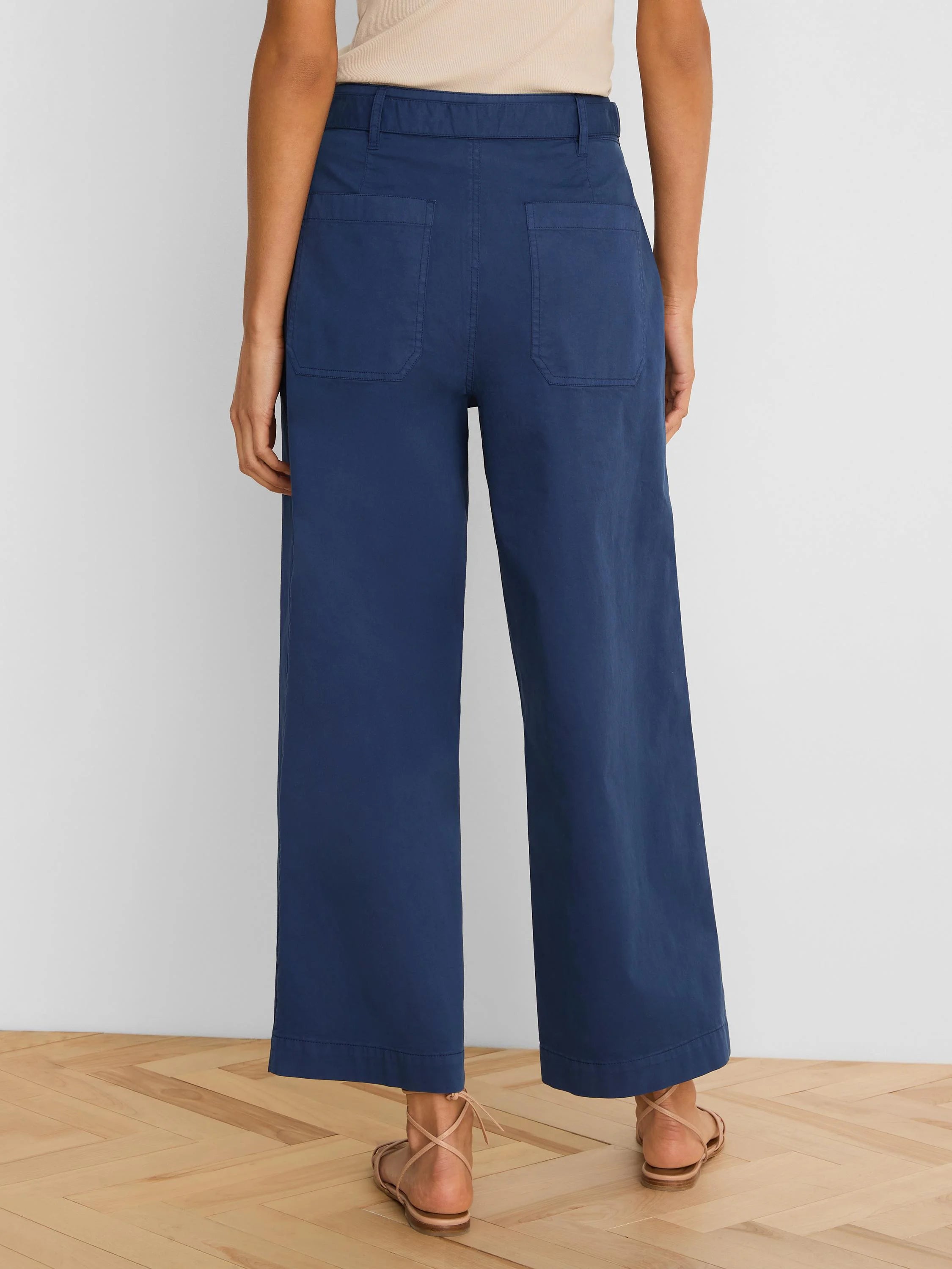 Dark blue wide-leg ankle pants with rear patch pockets and belt loops, shown from behind.