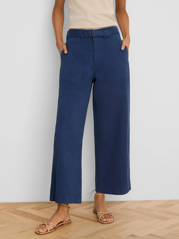 Dark blue wide-leg ankle pants with belted waist, front patch pockets, modeled on a person.
