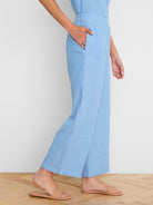 Light blue wide-leg gauze ankle pants with white vertical stripes. Model's hand in side pocket.
