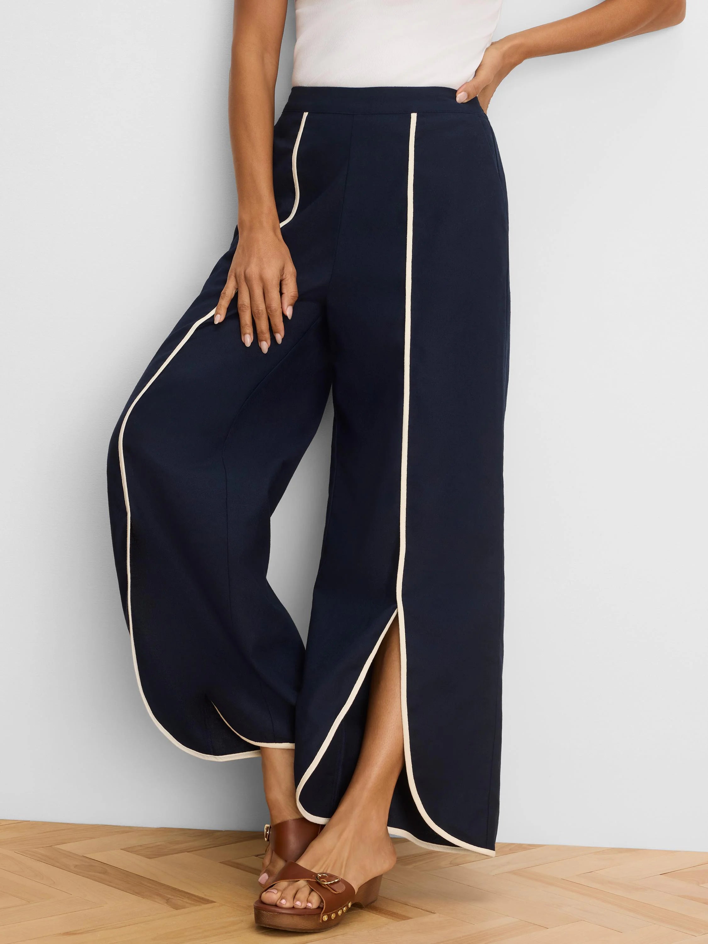 Navy wide leg pants with cream piping on outer seams, pockets, and a front split hem.
