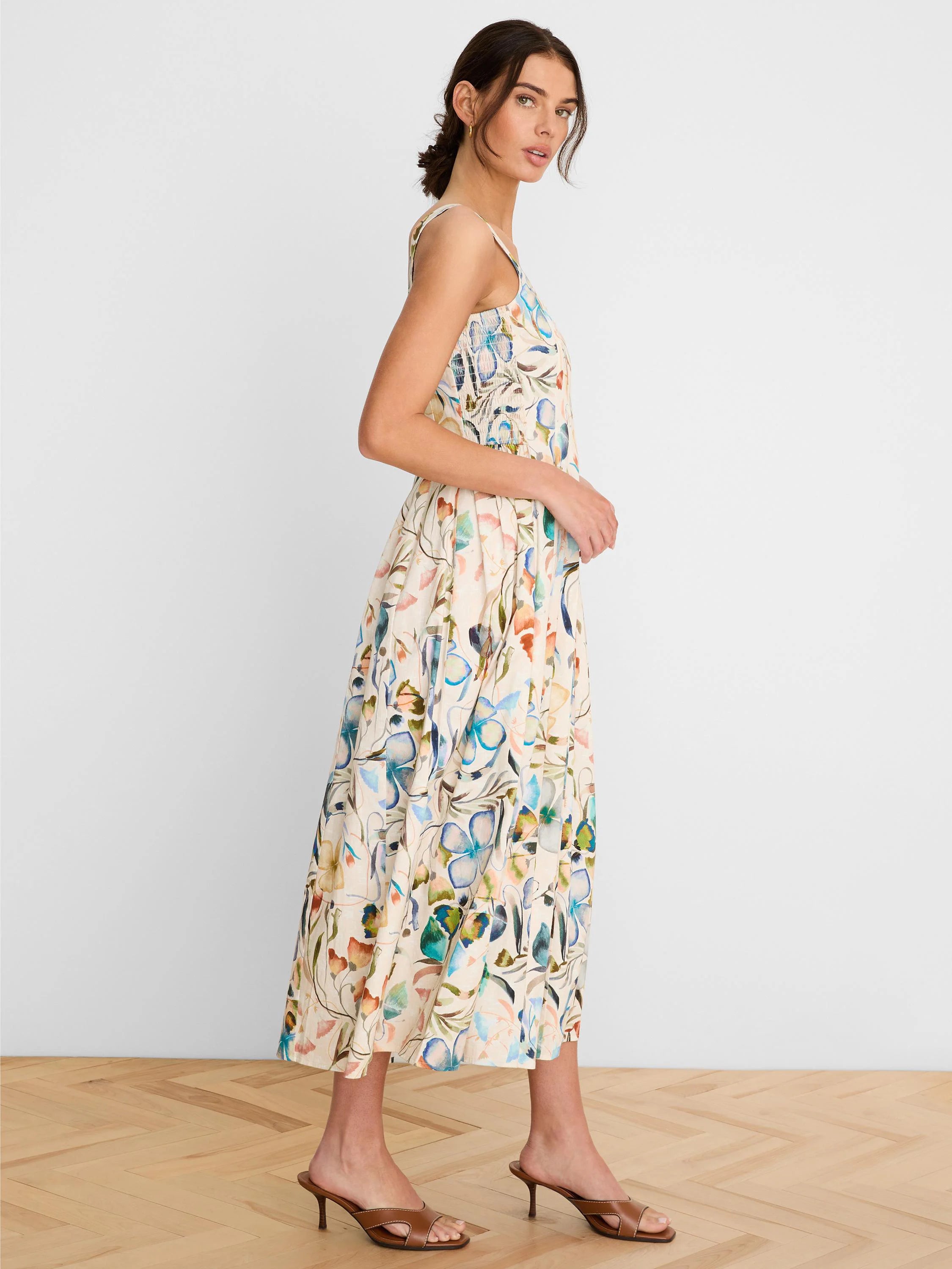 Cream midi dress with thin straps, smocked top, and a 'pressed flowers' print in blue, green, and orange.