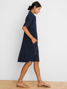 Navy dress with a collar, rolled short sleeves, side pockets, and white buttons on a side split. Above knee length.