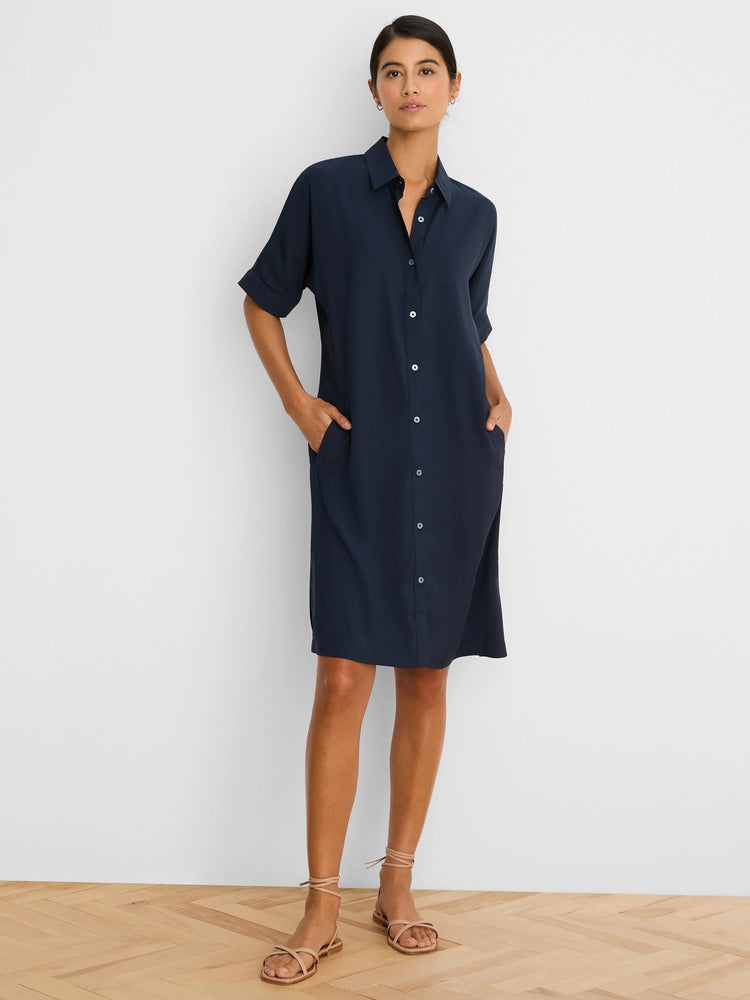Navy button-down dress with a collar, short rolled sleeves, white front buttons, and pockets. Hits above the knee.