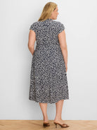 Cream leopard sketch print on navy midi dress, short sleeves, stand collar, tie waist, seen from back.