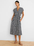 Midi dress with navy and white leopard sketch pattern, V-neck, short sleeves, tie belt, and pockets.