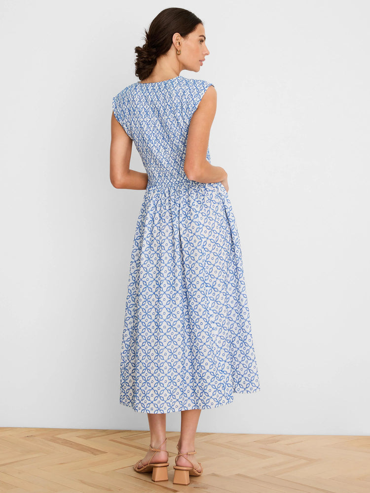 White sleeveless midi dress with blue embroidered tile pattern and smocked bodice.