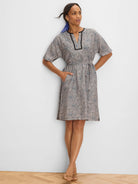 Sun speckle dress: light base with blue/dark dots. Black trim at V-neck, short sleeves, & sides. Drawstring waist, pockets.
