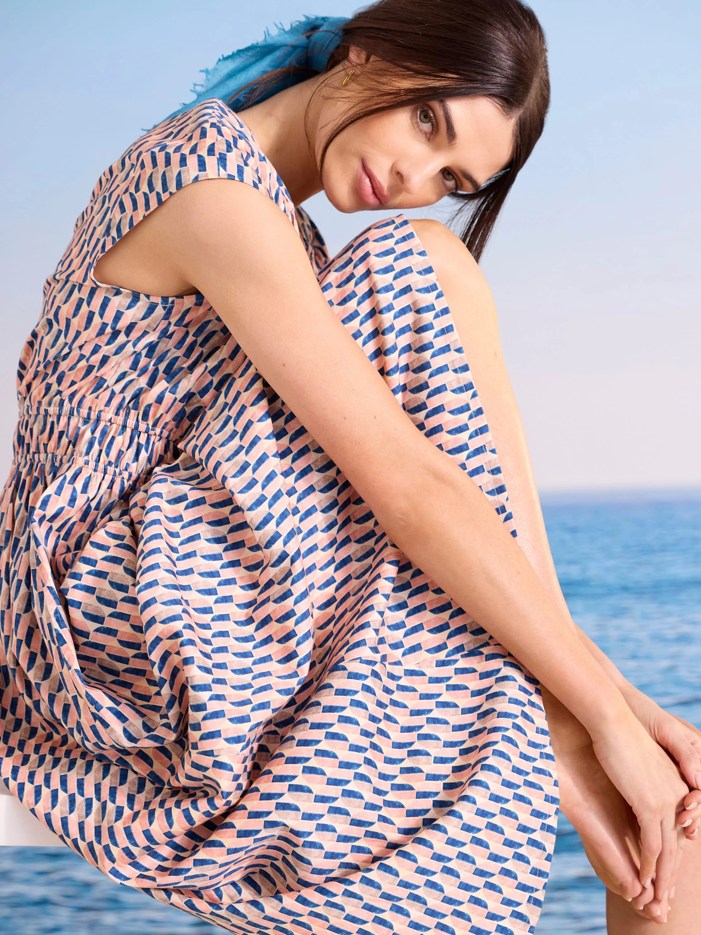 Cap sleeve dress with salmon pink, navy, and beige geometric arc pattern, elastic waist.