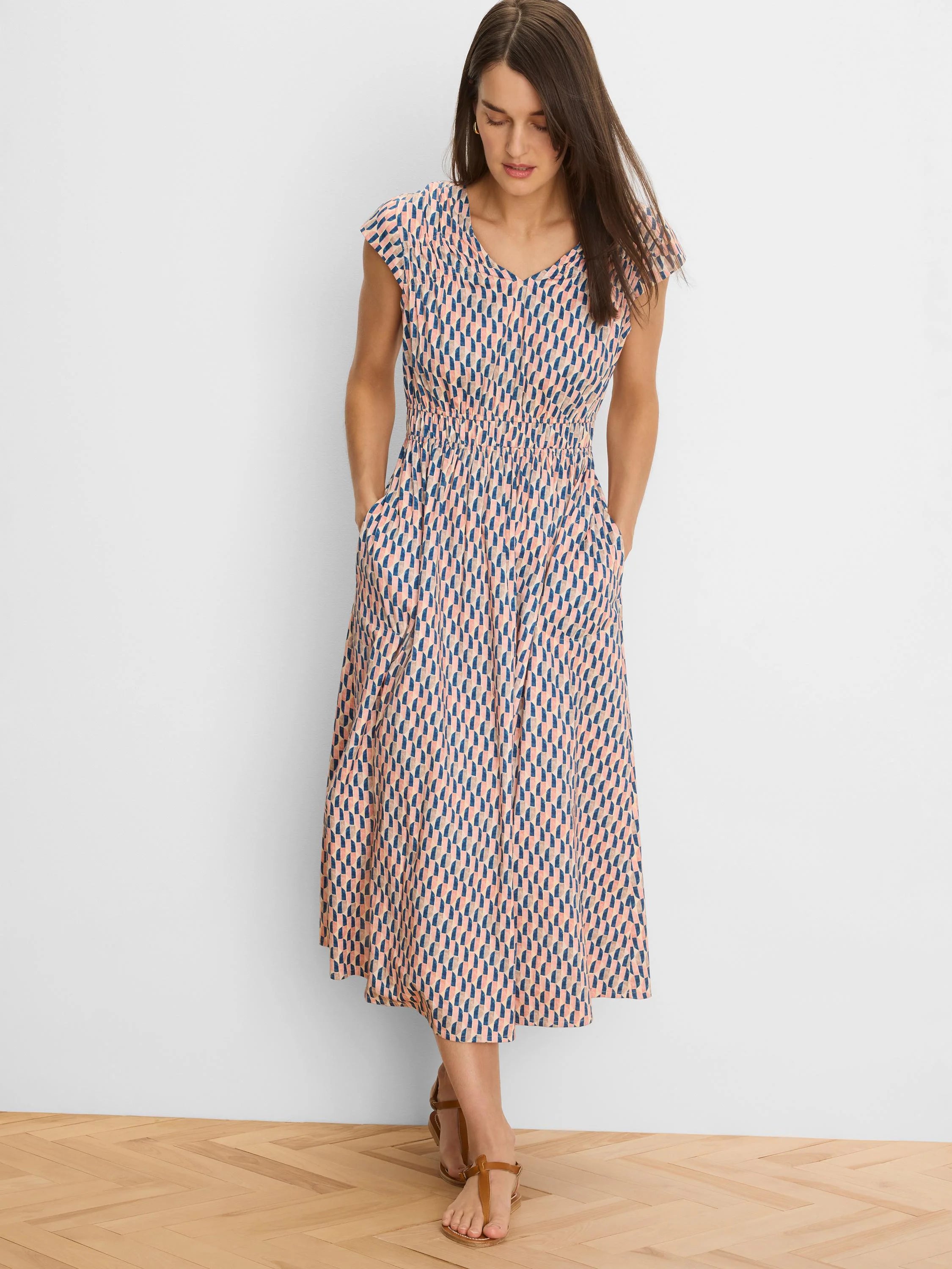 Cap sleeve V-neck midi dress with peach and navy geometric print, shirred waist, and pockets.