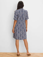 Navy shirt dress with blue, white, peach speckled pattern, cuffed short sleeves, above-knee. Shown from back.