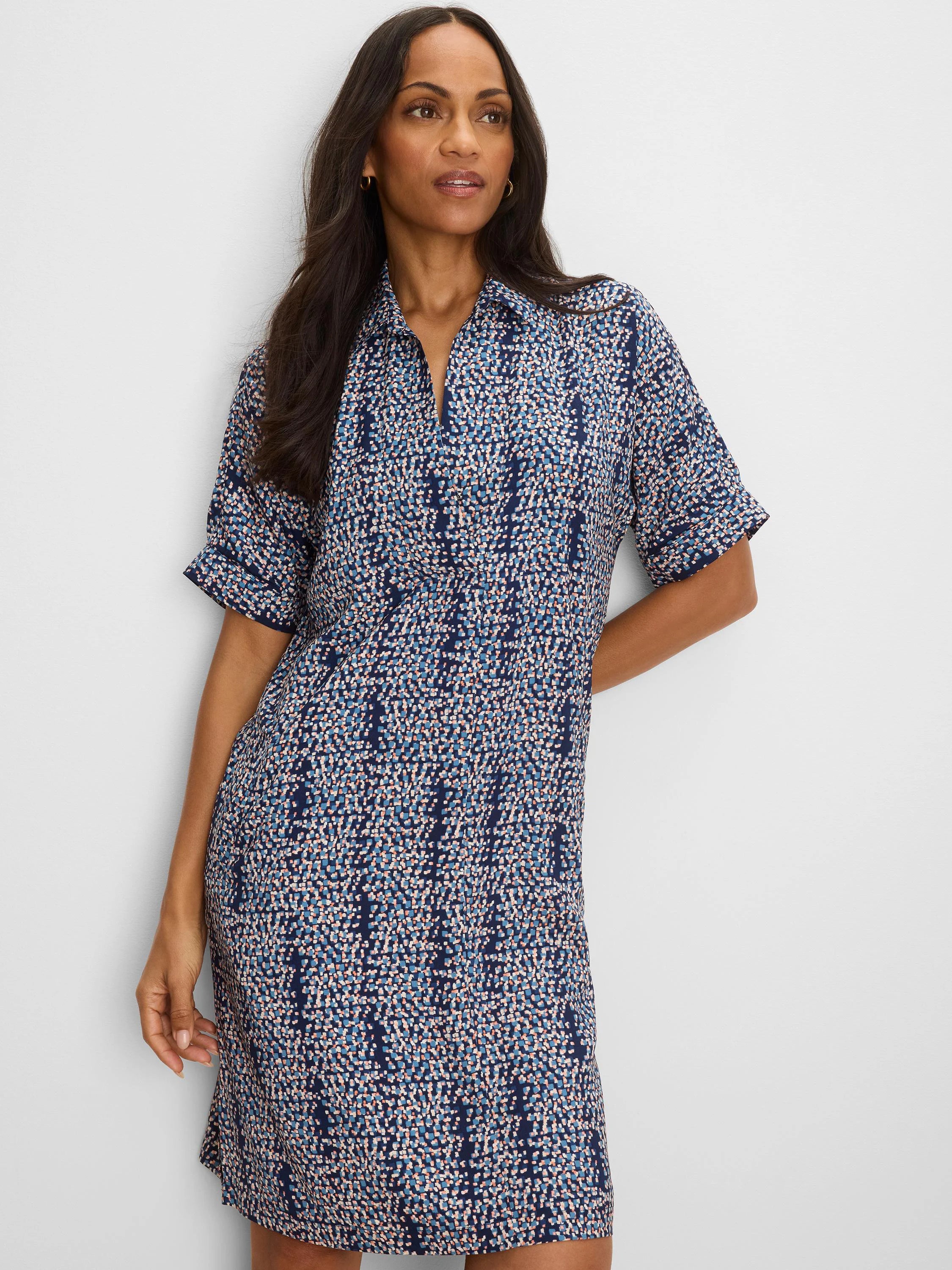 Navy blue shift dress with short cuffed sleeves, collared V-neck, and a scattered square print in light blue, peach, and...