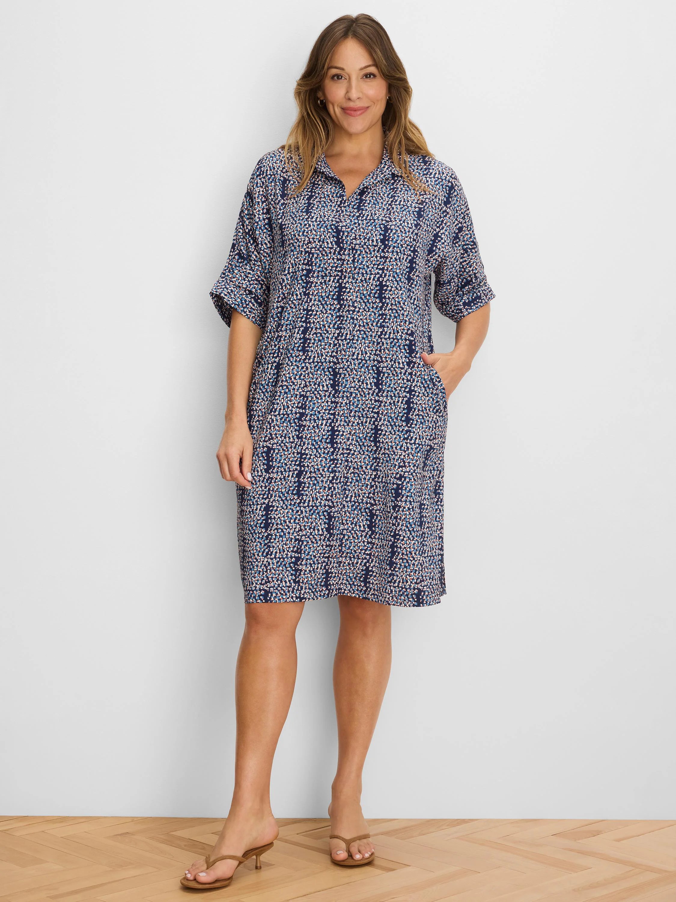 Navy dress with light blue, white, coral pixel pattern. V-neck, cuffed short sleeves, knee-length, pockets.
