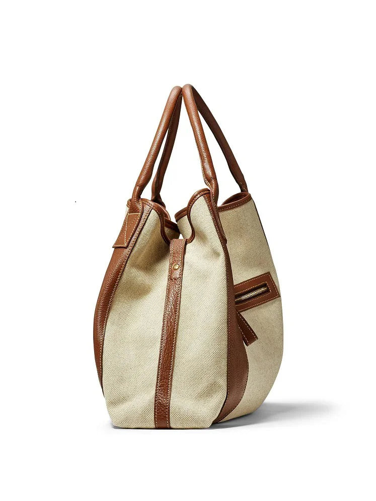 Light beige linen tote with brown leather handles, trim, and side zipper pocket.