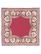 Square deep red fabric with an ornate cream floral border and a thin maroon outer edge.