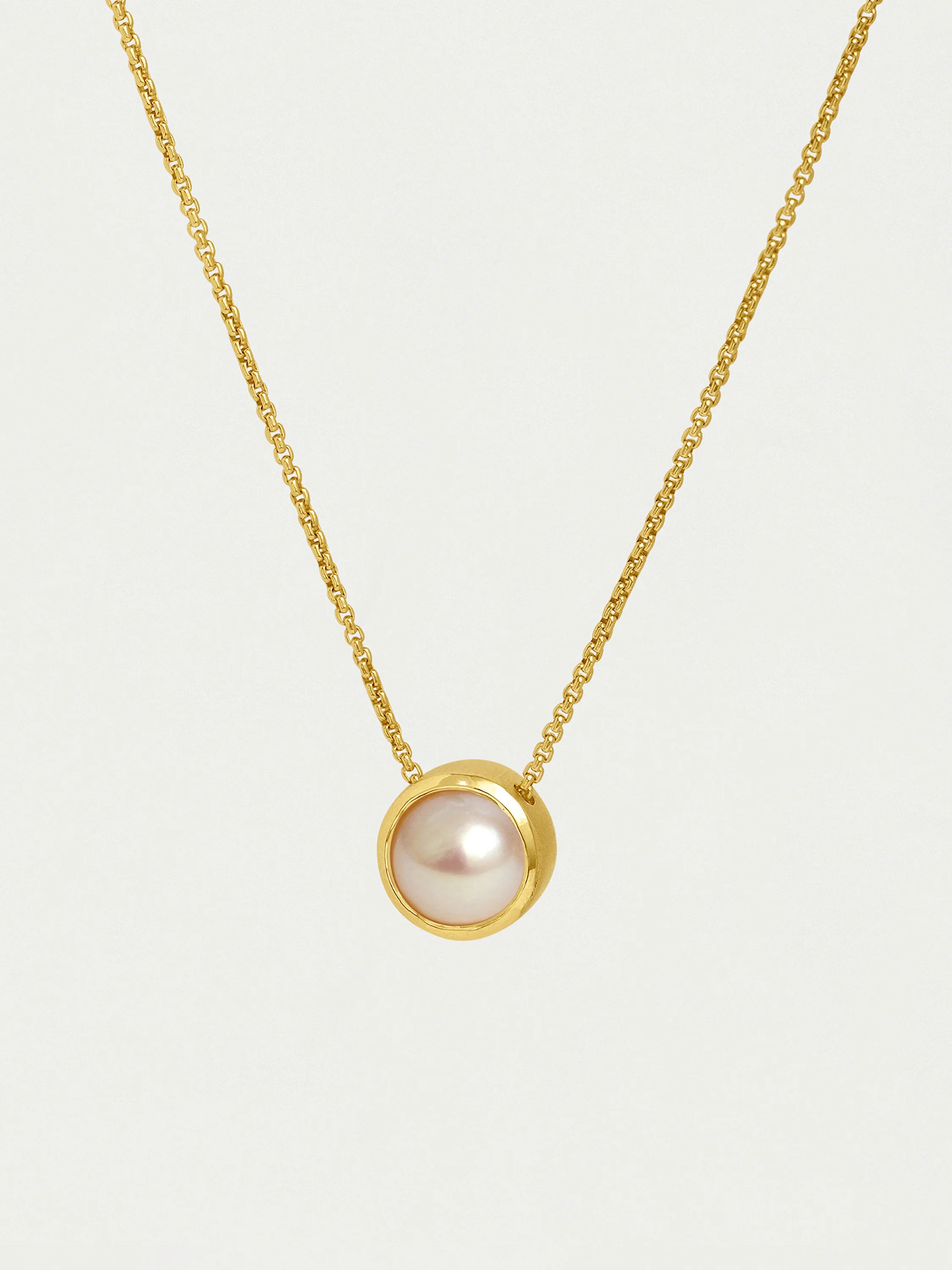 Gold chain necklace with a round, off-white pearl pendant.