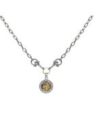 Silver chain necklace with a circular, antique gold coin pendant framed by small, clear stones.