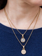 Gold necklace with two circular pendants.  Smaller pendant is fully pave-set; larger has a central gray coin-like element.