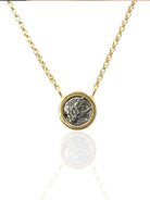 Gold chain necklace with a circular, gray coin-like pendant in a gold frame.