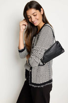 Black pebbled leather clutch, rectangular, with prominent dark metal rivets on the front and a top zipper closure.