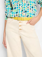 Yellow croc-embossed leather belt with gold buckle. Shown on model wearing off-white pants and teal/blue/green patterned...