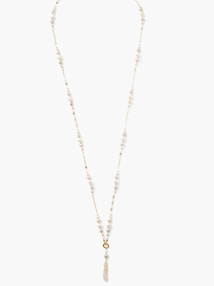 Long gold Y-necklace with irregular white pearls spaced along the chain, a gold ring, and an elongated pearl drop.