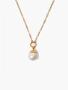 Gold chain necklace with large off-white pearl pendant; twisted gold detail at clasp.
