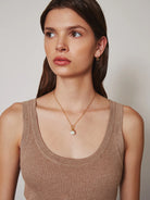 Gold chain necklace with a large off-white pearl pendant.