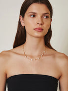 Delicate gold chain with spaced, irregular white pearls.