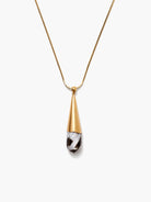 Gold snake chain necklace with a pendant: gold conical top, black & white striped mother-of-pearl teardrop.