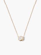 Thin gold chain necklace with a round, milky white stone pendant in an organic gold setting.
