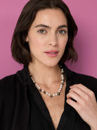 Off-white pearls mixed with irregular, faceted stones in dark green, grey, and iridescent blue.