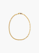 Gold oval-link chain necklace with a small smokey quartz stone near the clasp.